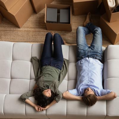 Overhead of a young couple taking a break on the sofa after moving to a new home.