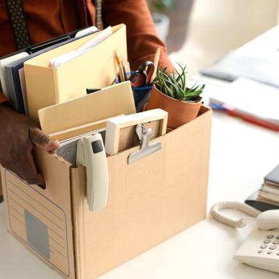An office worker packing personal office items to a box. 