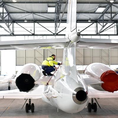 Airport workers check an aircraft for safety in a hangar.