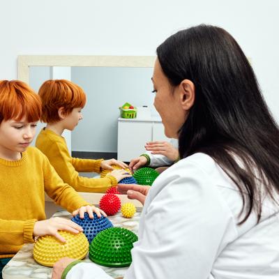 An occupational therapist using sensory integration therapy to a child patient in a clinic.