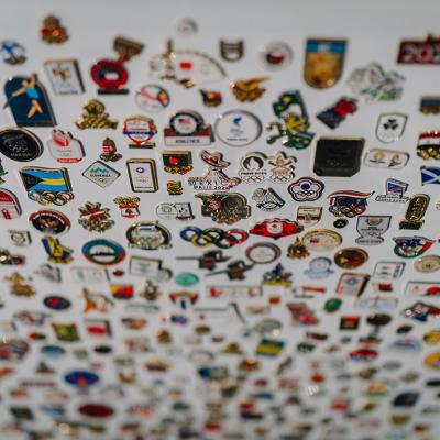 Olympic enamel pins from different countries arranged on a white board showcasing.