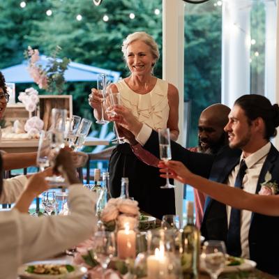 Guests raising glasses during a joyful toast from a wedding reception dinner.