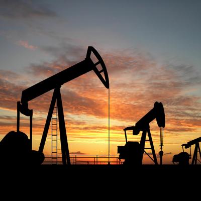 Silhouette of gas pumps machinery during sunset.