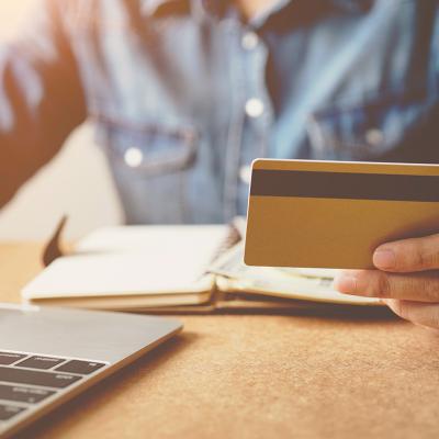 A person checking his credit card while reviewing finances from a laptop.