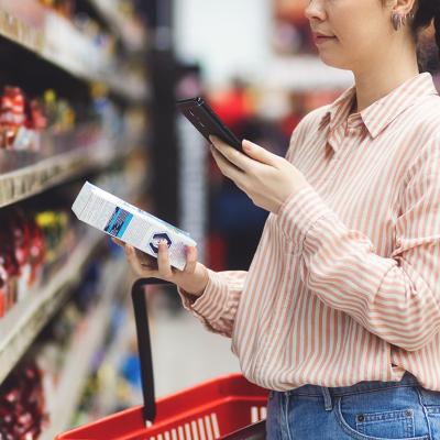 A person scanning a QR code of a product from her smartphone in a supermarket.