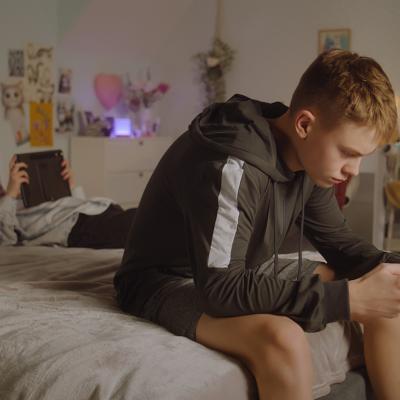 Teenage siblings at home scrolling through their phones.