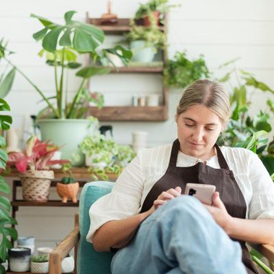 A female small garden business owner browsing information using a smartphone.