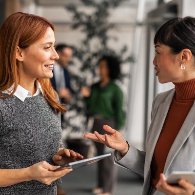 Two female professionals engaged in a positive discussion in an office.
