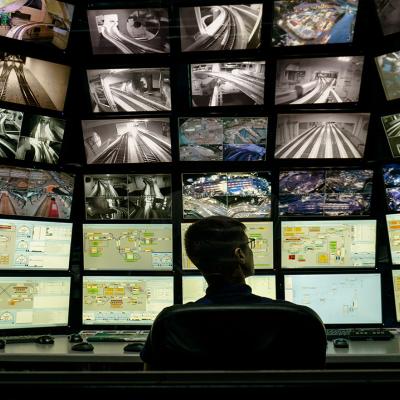 A security staff member overlooking a multiple display monitoring system.