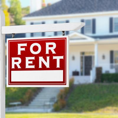 A For Rent sign placed in front of a residential house.