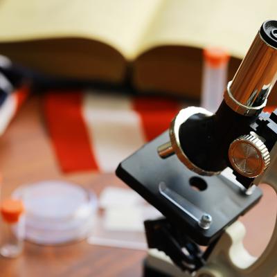 A microscope with an open book and the US flag in the backdrop as a concept of scientific research.