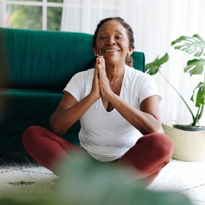 A elderly person practicing meditation in a prayer pose during a yoga session.