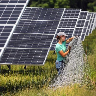 A worker organize fencing materials along solar panels at the Fitchburg Renewables solar farm in Massachusetts.