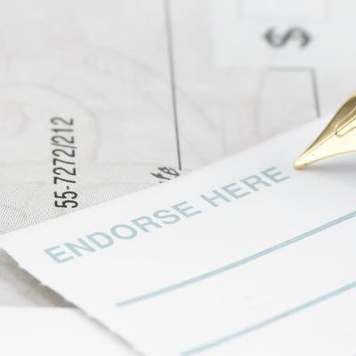A pen signing an endorsement note to a check.