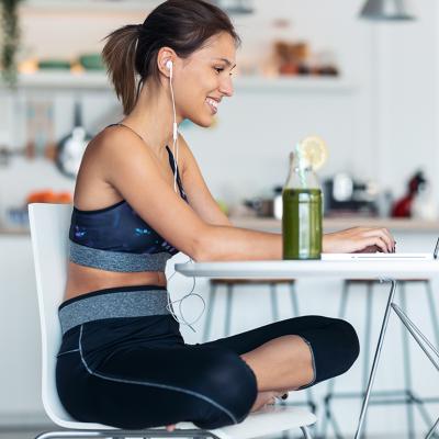 A young woman in athleisure wear working from her home's kitchen.