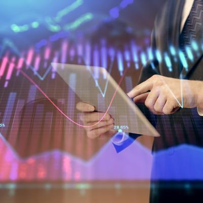 A financial marketer using a tablet with an overlay of forex graphs.