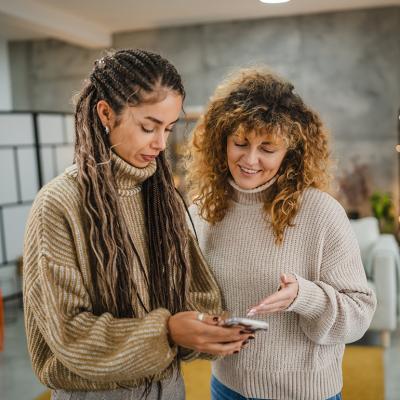 Two friends checking online and making digital payments from a smartphone.
