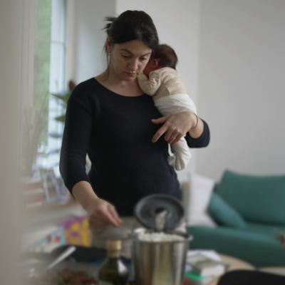 A mother holding her newborn baby multitasking at home.