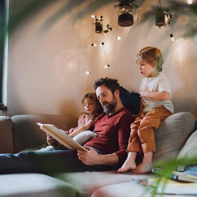 A father with his two children looking at a photo album at home together.