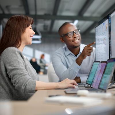 Two auditors carefully review financial data on a computer screen.