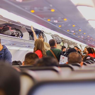 Passengers on a plane storing their carry-on luggage in the overhead compartments.