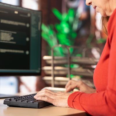 A female employee typing on a keyboard while working in an office.