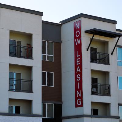 A modern apartment building with a huge 'now leasing' signage.