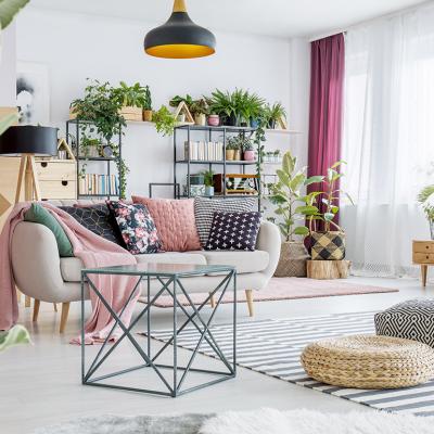 An interior of a spacious living room with plants, poufs, sofas, and cabinets.