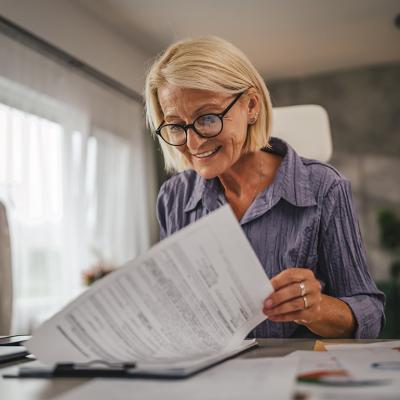 A middle-aged woman reviewing insurance documents at home.