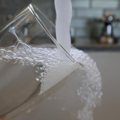 Water running from a kitchen faucet to fill a glass.
