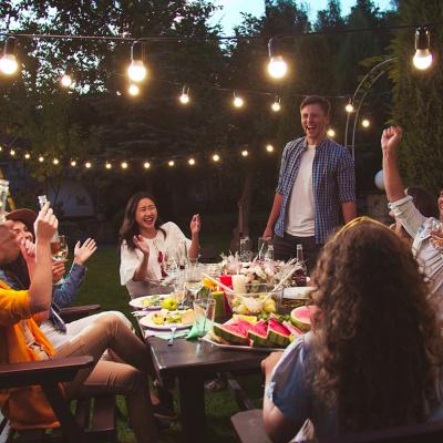 A group of friends laughing together and enjoying their time during a backyard party.