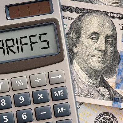 A calculator displaying the word 'tariffs' on top of a US dollar banknote.