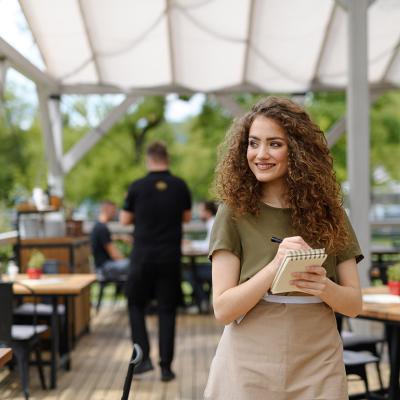 A waitress standing in a restaurant terrace after writing down an order.