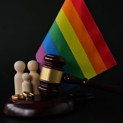 An LGBTQ+ rainbow flag with a figure of a family and judge's gavel as a concept of same-sex divorce.