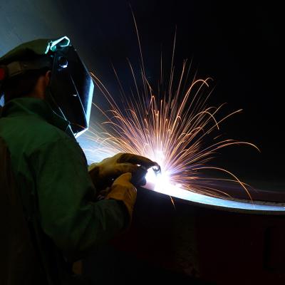 A worker welding a very large steel pipe.