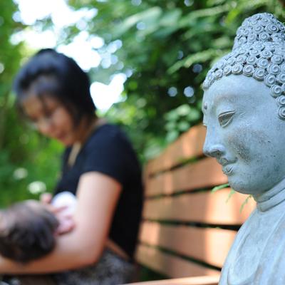 A Buddhist mother carrying and feeding her child outside in a park.
