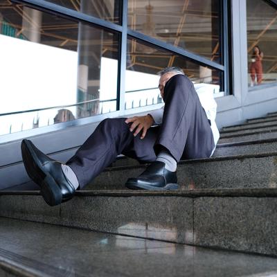 An elderly person getting injured after falling down the stairs in a workplace.