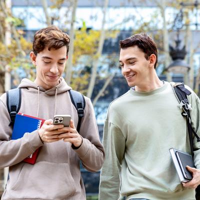 University students checking online content from a smartphone while outdoors in the campus.