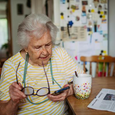 An elderly woman using a smartphone at home.
