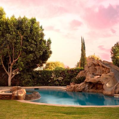 A modern backyard pool with rock waterfalls and slide.
