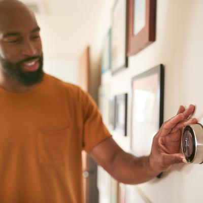 A man adjusting the thermostat at home.