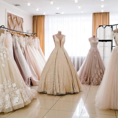 Wedding dresses on hangers and mannequins displayed in a bridal studio.