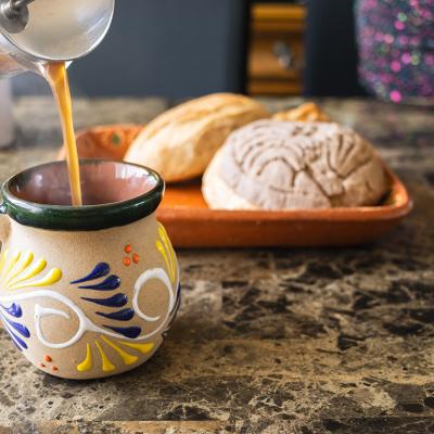 Coffee being poured in a traditional Mexican cup with bread on the side.