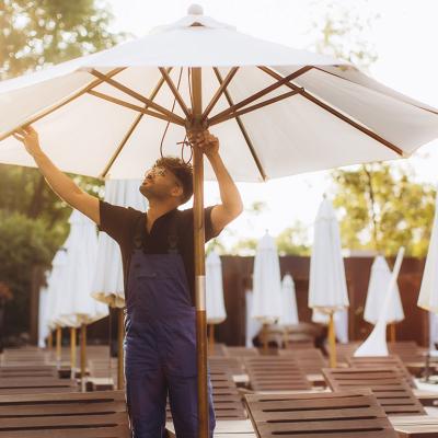 A hotel officer setting up a parasol beside the hotel's pool before guests' arrival.