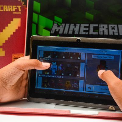 A young child paying Minecraft on a digital tablet.