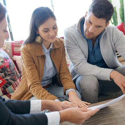A couple reviewing a home investment contract with supervision from a financial advisor.