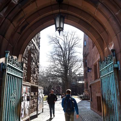 Students passing through an entrance to Yale University's old campus in New Haven, Connecticut, USA. 