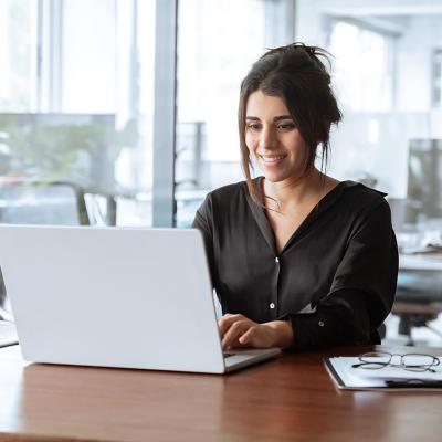A focused young businesswoman working with a laptop in an office.