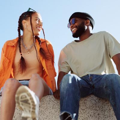 A couple bonding together while enjoying in a sitting wall outdoors.