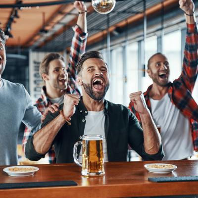 A group of men cheering and drinking beer while watching a sports game.